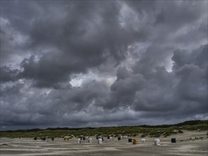 Threatening sky over an empty beach with scattered beach chairs, colourful beach chairs on the