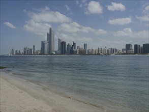 The skyline with skyscrapers of a modern city on the seashore under a slightly cloudy sky,