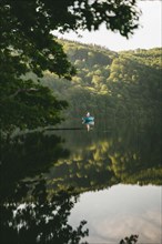 A kayak on a calm lake, surrounded by trees, in the light of dawn. Laacher See, Glees Germany