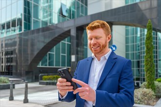 Businessman smiling while using the mobile phone standing in the city
