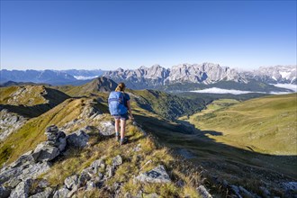 Mountaineer on a grassy ridge, mountain panorama, view of rocky mountain peaks of the Sesto