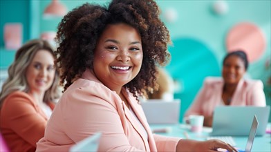 Curly-haired woman in a pink professional outfit smiling while working on laptop with team, ai