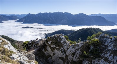 Hiker at Ettaler Manndl, view over mountain landscape and sea of clouds, high fog in the valley,