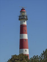Close-up of a red and white striped lighthouse with a clear blue sky, red and white lighthouse by