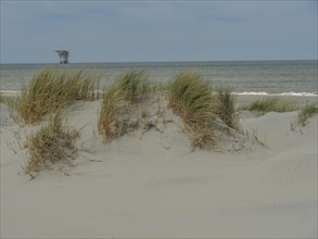Calm sea with a structure in the water, seen from behind sand dunes with reeds, dunes by the sea