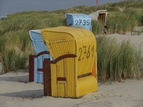 Close-up of yellow and blue beach chairs in the dunes on the beach, colourful beach chairs on the