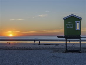 Beach view at sunset with a green beach hut and people in the background, beautiful sunset on the