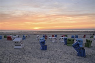 Beach chairs in different colours on the beach at sunset, many colourful beach chairs on a warm