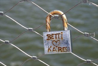 Rusty padlock, love lock, with the inscription Betti Herz Kares on a bridge railing, symbol of old