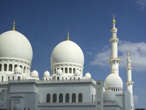 Beautiful mosque with white domes and high minarets against a clear blue sky, large mosque with