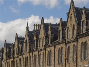 Row of old stone houses with numerous gables and windows under a cloudy sky, house facades and a