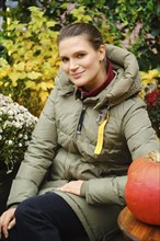 Outdoor portrait of cute mid age woman among autumn flowers
