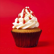 Cupcake with swirls of buttercream frosting in vanilla against red background, AI generated