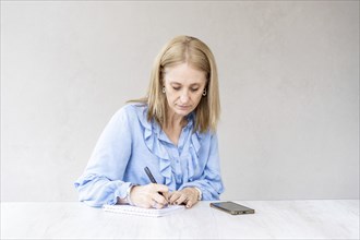 Beautiful mid-adult woman is writing in her notebook