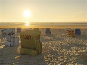 Several beach chairs on the beach at sunset, Shadows cast long lines on the sand, Sunset on a quiet