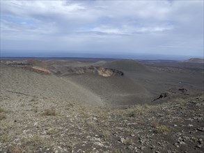 Vast desert landscape with views of the ocean and sky with clouds, barren landscape of lava