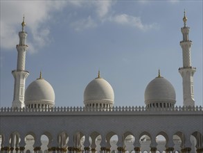 Mosque with white domes and several minarets under a partly cloudy sky, beautiful mosque with white