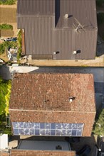 Aerial shot of a residential area showing roofs with damaged solar panels and brown tiles
