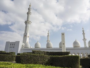 Imposing mosque with domes, minaret and manicured gardens against a cloudy sky, beautiful mosque