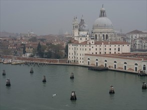 Venetian buildings with domes and green water in a misty scenery, church towers and historic