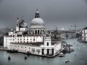 A view of Venice's church, canals and boats on a cloudy day with historic buildings in the