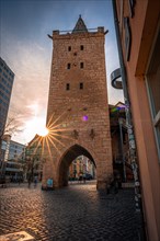 The Johannistor in the city centre of Jena at sunset with sun star and blue sky, Jena, Thuringia,