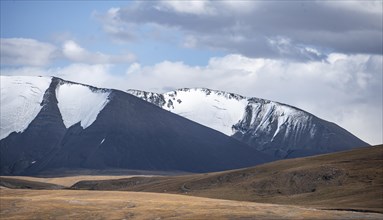 Autumnal plateau with brown grass, glaciated and snow-covered peaks, Ak Shyrak Mountains, near the