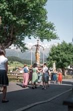 A procession with a statue of the Virgin Mary and traditionally dressed people. Nauders, Austria,