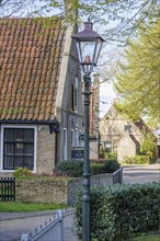 Well-kept rural street with a traditional house and a street lamp surrounded by green spring