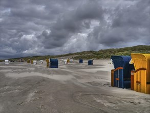 Deserted beach with many beach chairs under a dramatically cloudy sky, colourful beach chairs on