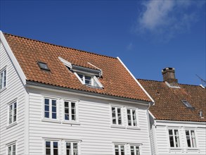 Traditional white houses with orange roofs under a blue sky with few clouds, white wooden houses