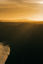 Sunset with river and the silhouette of trees and mountains. Niederfell, Germany, Europe