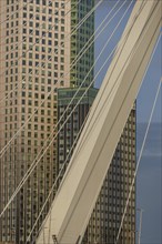 Cityscape with modern skyscrapers and a bridge element in the foreground. Bright blue sky, skyline