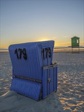 Blue beach chair on the beach at sunset with a calm sky and sand, beautiful sunset on the beach of