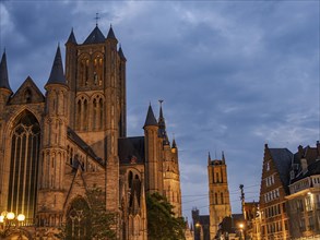 Illuminated gothic cathedral and church towers in a historic city at night, historic buildings with