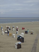 Single beach chairs are scattered on the empty, quiet beach under a cloudy sky, beach chairs and