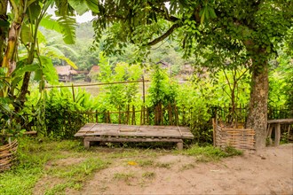 Wooden table in front of bamboo fence in small southeast Asian farming community in Chiang Khan,