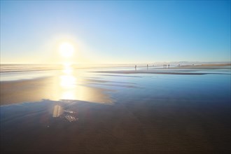 Atlantic ocean sunset with sun and surging waves at wide sand of Fonte da Telha beach, Costa da