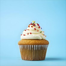 Cupcake with swirls of buttercream frosting in vanilla against blue background, AI generated