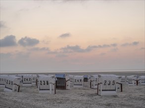 Empty beach chairs on the beach at dusk, pastel coloured sky and calm atmosphere, setting sun on a