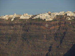Santorini's characteristic whitewashed houses clinging spectacularly to the island's steep cliffs,