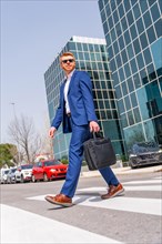 Vertical full length of a stylish cool businessman crossing the street in the city