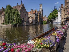 Picturesque scene with old buildings along a canal and colourful blooming flowers in the foreground