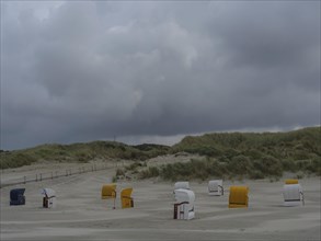 Empty beach with dark clouds and scattered colourful beach chairs, colourful beach chairs on the