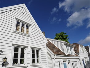 White wooden houses with red roof tiles and windows under a blue sky on a sunny day, white wooden