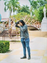 Young photographer taking photos on the street. Male photographer taking photos in a public park,