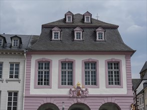 A historic pink building with windows and dormers under a cloudy sky, historic house fronts with a