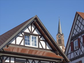 Detail of a half-timbered house with a view of a church tower under a bright blue sky, old