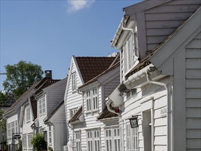 Rows of white wooden houses with numerous windows and blue sky in the background, white wooden