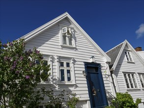 White house with blue painted door and red tiled roof under clear sky, white wooden houses with red